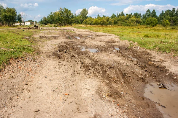 Broken dirt road with puddles in the forest — Stock Photo, Image