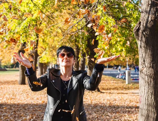 Giovane donna vomita foglie gialle nel parco in autunno — Foto Stock