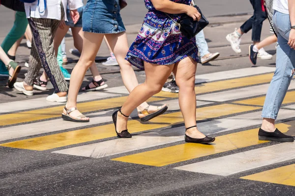 people crossing the street at pedestrian crossing on sunny