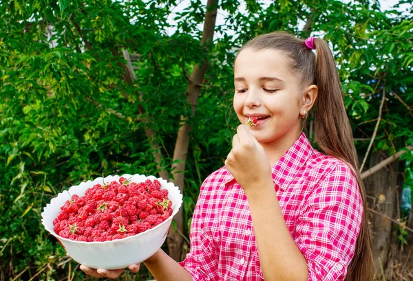 Tiener meisje houdt een kom frambozen in de tuin — Stockfoto