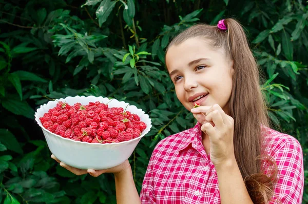 Tiener meisje houdt een kom frambozen in de tuin — Stockfoto