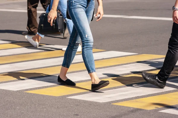 Piernas de jóvenes peatones caminando en el paso de peatones — Foto de Stock