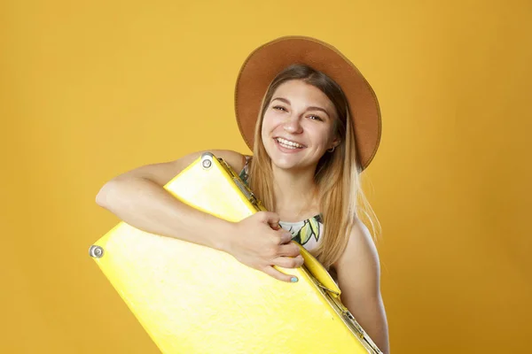 Mujer turista feliz con caja amarilla de viaje y tarjeta de crédito. Retrato de estudio. Concepto de vacaciones . —  Fotos de Stock