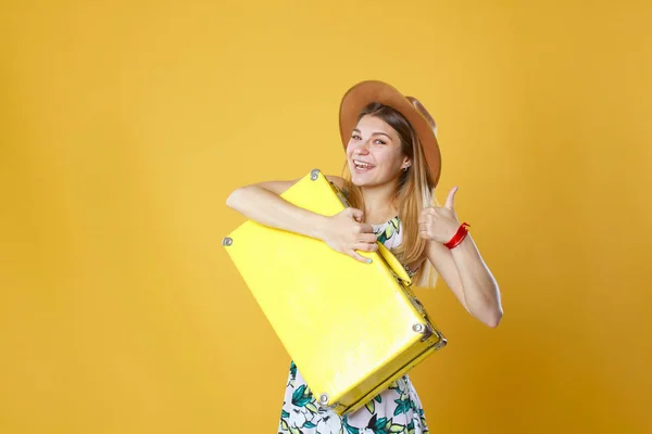 Mujer turista feliz con caja amarilla de viaje y tarjeta de crédito. Retrato de estudio. Concepto de vacaciones . — Foto de Stock