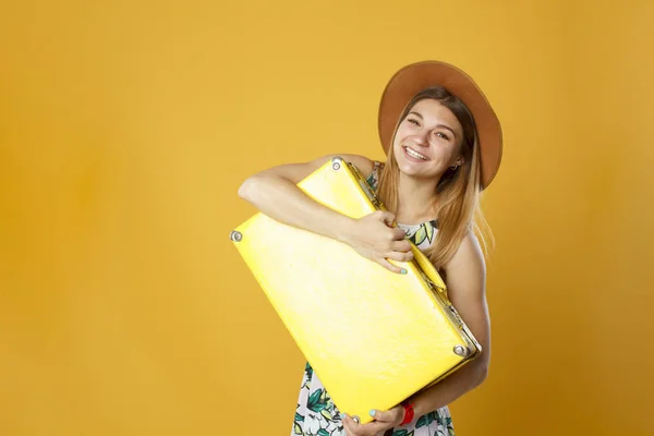 Mujer turista feliz con caja amarilla de viaje y tarjeta de crédito. Retrato de estudio. Concepto de vacaciones . —  Fotos de Stock