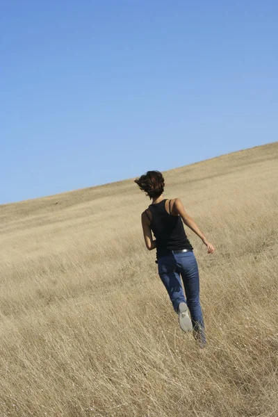 Menina adulta fugindo através do campo. Belo dia quente de verão. Conceito de liberdade — Fotografia de Stock