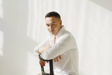 Yakışıklı esmer adam, gün ışığında stüdyoda poz veriyor.