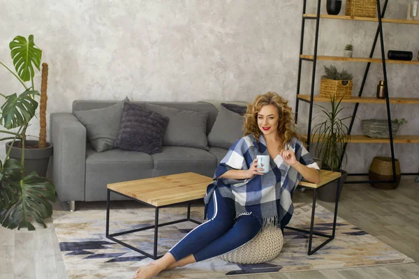 Ritratto di giovane donna bionda in salotto luminoso bevendo tazza di tè o caffè — Foto Stock