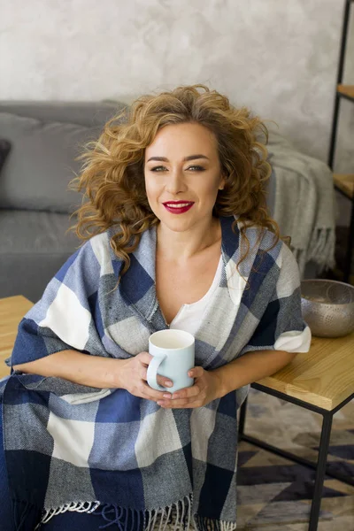 Retrato de mulher loira jovem na sala de estar brilhante beber xícara de chá ou café — Fotografia de Stock