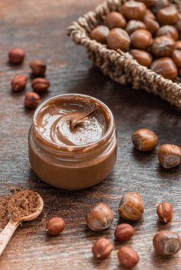 Lezzetli çikolata, fındık ezmesi ve ahşap bir masada fındık dolu cam kavanoz..