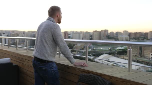 Man looks at the city from the roof of the hotel — Stock Footage Man Looks City Roof Hotel Stock Footage