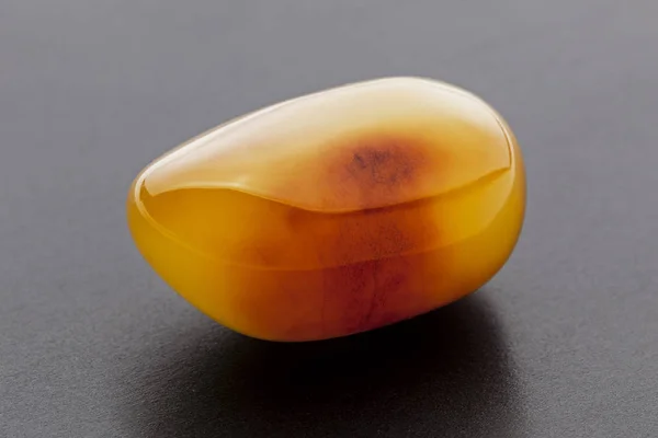 Natuurlijke Amber. Een stukje geel ondoorzichtige natuurlijke Amber op donkergrijze achtergrond. — Stockfoto