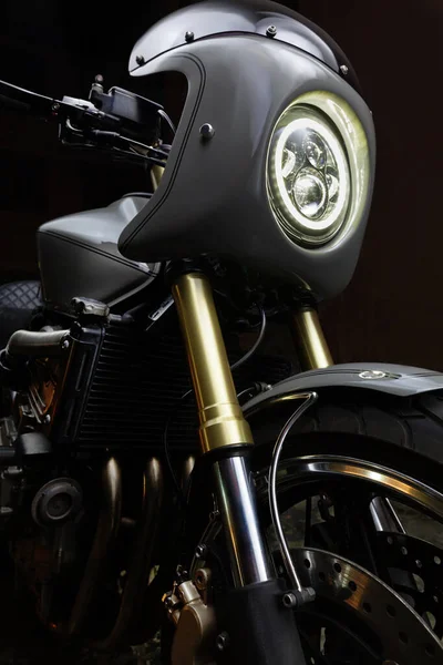 Custom caferacer motorbike on dark background with its headlight on. — Stock Photo, Image