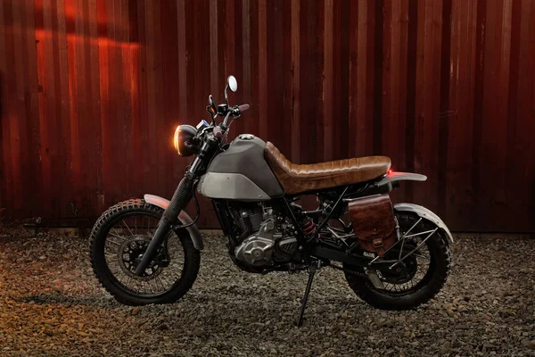 Moto scrambler personalizzata su uno sfondo contenitore arrugginito. — Foto Stock