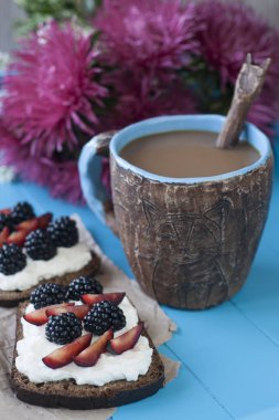 Tatlı peynir ve çilek, bir fincan kahve mavi ahşap arka planda sandviç
