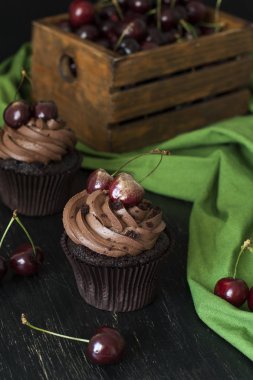 Vişne ve kiraz siyah bir zemin üzerine bir ahşap kutu ile lezzetli çikolata cupcakes