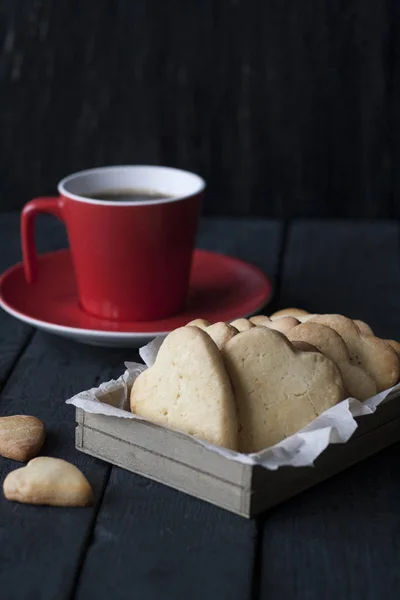 Tasty homemade gingerbread and coffee in a red cup on a black wooden background.