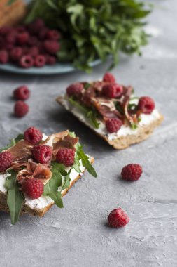 Bütün tahıl ekmeği, ev yapımı peynir, roka, jambon ve sulu ahududu sandviçle. Sağlıklı snack.