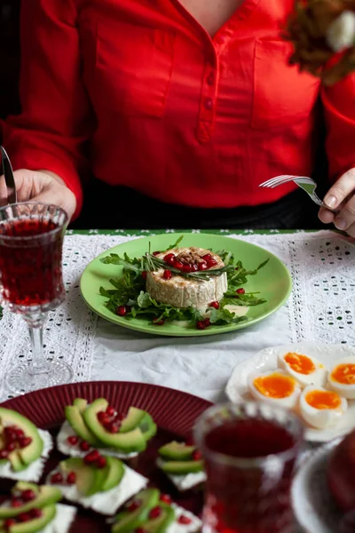 Een vrouw in een rode blouse snijdt een gebakken camemberle — Stockfoto