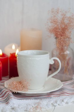 Çizgili bir masa örtüsü üzerinde siyah çay sıcak bir fincan, mum mumlar, bir 