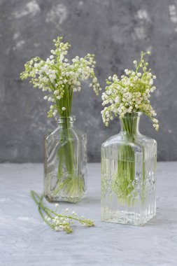 Gra üzerinde cam vazolar içinde vadideki zambaklar.