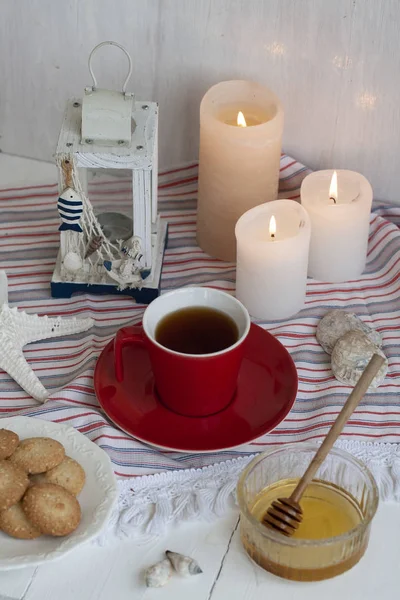 Eine Tasse schwarzen Tee mit hausgemachten Keksen auf einer gestreiften Tischdecke — Stockfoto