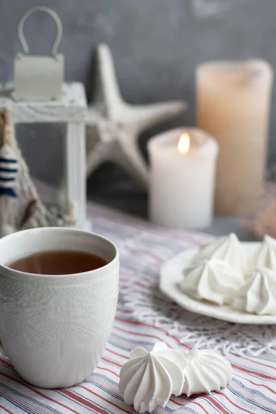 Eine heiße Tasse schwarzen Tee mit einem Teller luftiger Baiser auf einem Streifen — Stockfoto