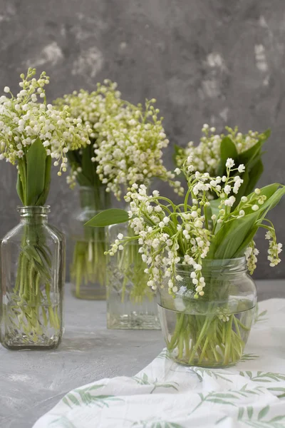 Wresh bouquets de lis de la vallée dans des vases en verre sur le whi — Photo