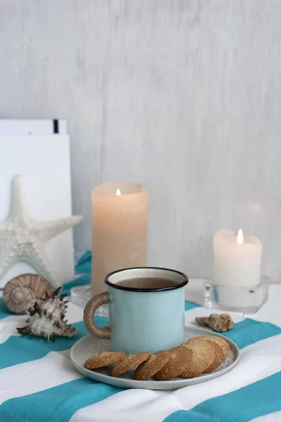 Una taza caliente de té negro con galletas caseras en una mesa a rayas Imagen de stock