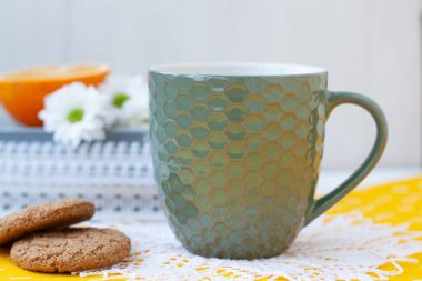Bir çalışma molası: bir fincan çay, kurabiye ve bir portakal yarım.