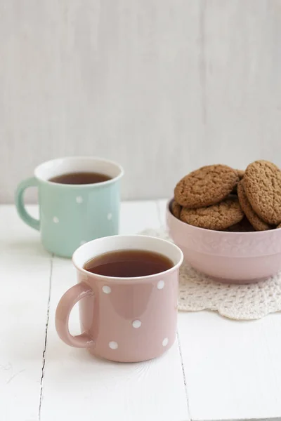 A tasty snack: two cups of tea and a bowl of cookies. — Stock Photo, Image