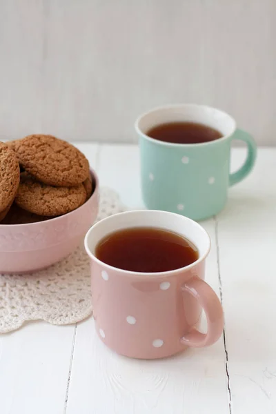 Een lekkere snack: twee kopjes thee en een kom koekjes — Stockfoto