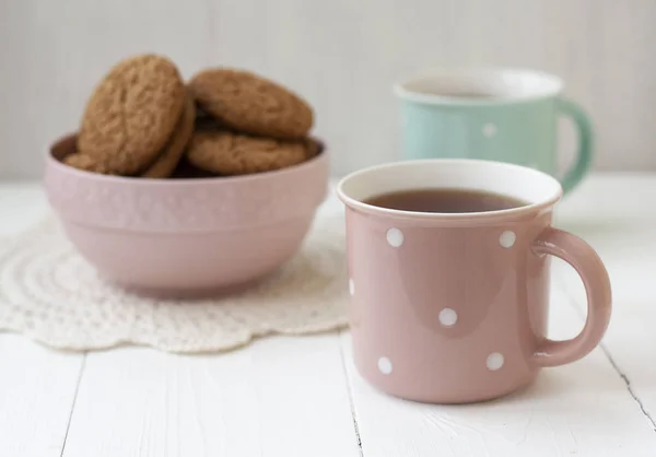 Un tentempié sabroso: dos tazas de té y un tazón de galletas . —  Fotos de Stock