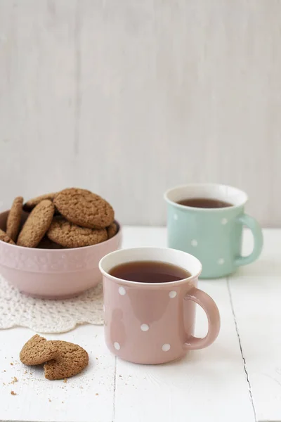 Um lanche saboroso: duas xícaras de chá e uma tigela de biscoitos . — Fotografia de Stock