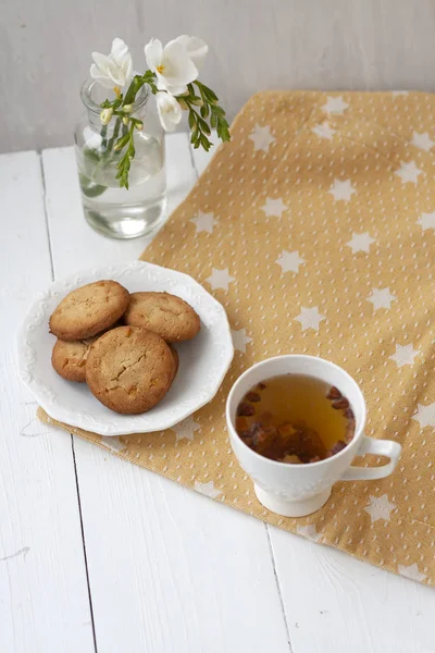 Un tentempié sabroso: una taza de té y un plato de galletas . —  Fotos de Stock