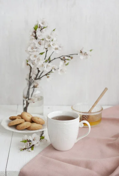 En välsmakande paus: en kopp te, en skål med honung och en tallrik — Stockfoto