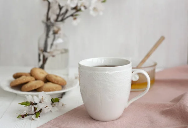 Un sabroso descanso: una taza de té, un tazón de miel y un plato de cocinero —  Fotos de Stock