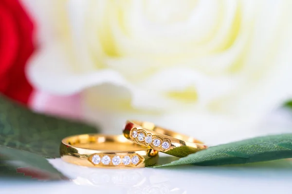 Close up Gold ring and Red roses on white  background, Wedding concept with roses and gold rings