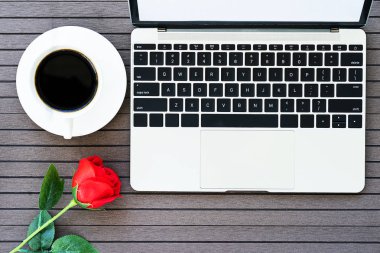 Top view kahve saati sevgililer günü konsepti, dizüstü bilgisayarlı masa, defter, kahve fincanı, kırmızı gül.