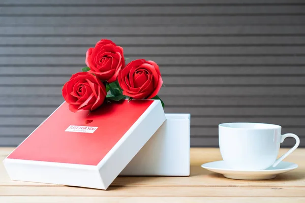 关闭红色玫瑰和礼品盒与咖啡杯在木材背景 情人节概念与玫瑰和红色盒子 — 图库照片