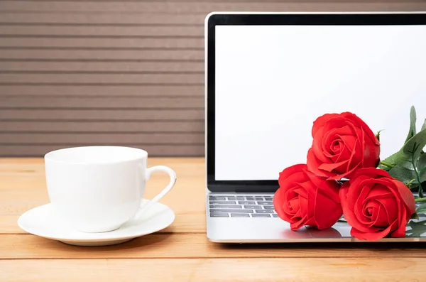 Red rose and coffee cup with laptop mockup on wood background, Valentine concept