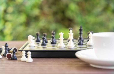 Kahve fincanları ahşap masada, satranç tahtası ve parçaları dinlenmek için.