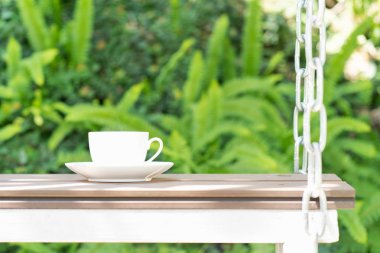 Kahve fincanı yeşil bahçe gevşeme saatinde zincirlerle askıya alınmış.