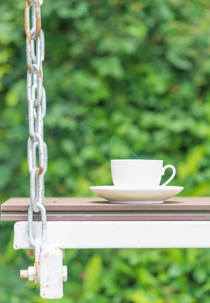 Coffee cup on seat suspended by chains — Stock Photo, Image
