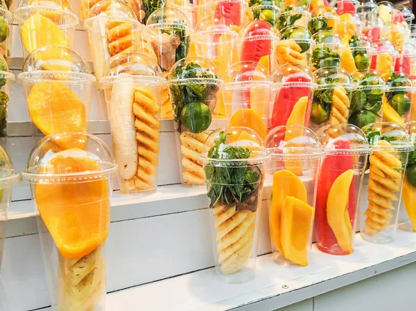 Mélanger les fruits dans un verre en plastique sur des étagères en bois — Photo