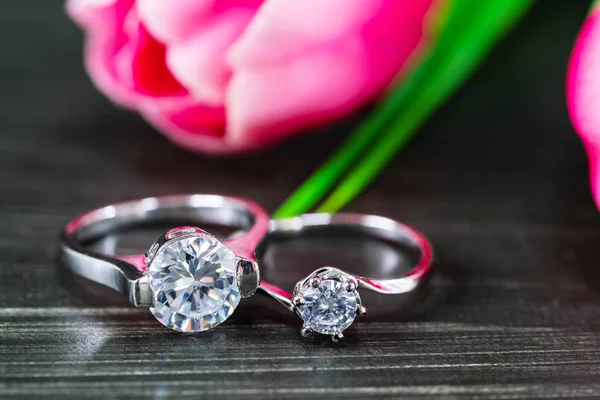 Anillos de boda de diamantes con flor de tulipán sobre fondo negro —  Fotos de Stock