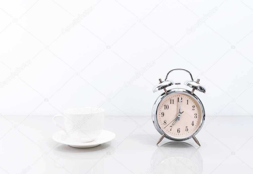 Silver alarm clock and coffee cup