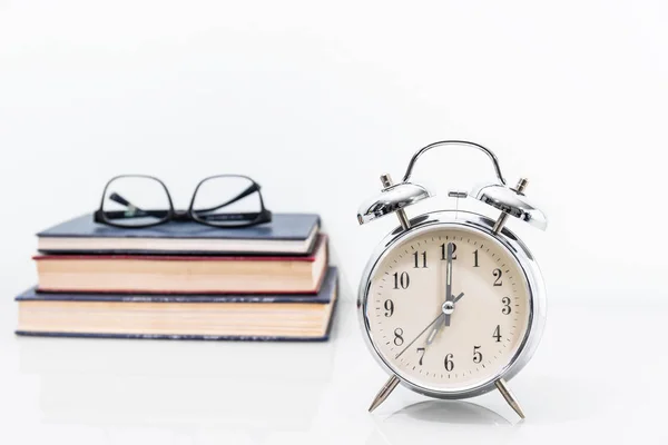 Reloj despertador con libro viejo con anteojos —  Fotos de Stock