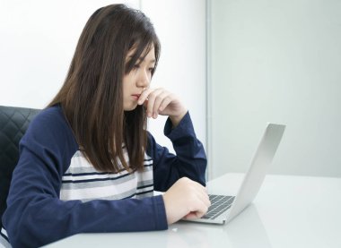 Oturma odasında oturan genç kız öğrenci bilgisayarla internetten öğreniyor.