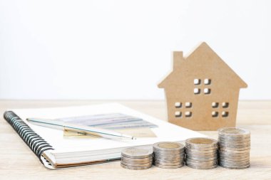 Ev modeli ve bankacılık konsepti için masanın üzerinde madeni paralar olan not defteri.